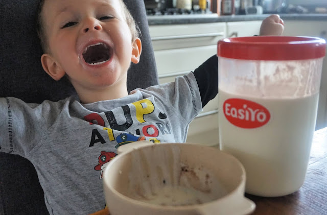 toddler posing with an easiyo and empty bowl of yoghurt