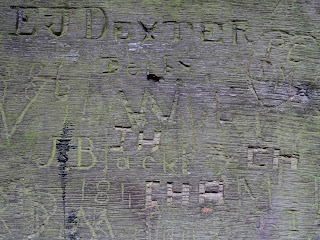 A photograph showing graffiti carved into the wood of one of the castle doors.  It is mainly initials and dates.  Photograph by Kevin Nosferatu for the Skulferatu Project.