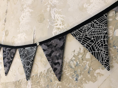 SnugglebumsUK bunting with black triangles alternating bat print and cobweb print