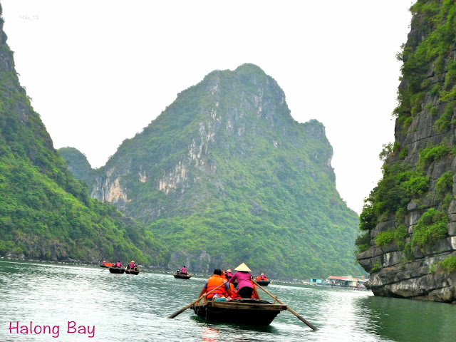 boats with tourists visiting a small village on Halong Bay