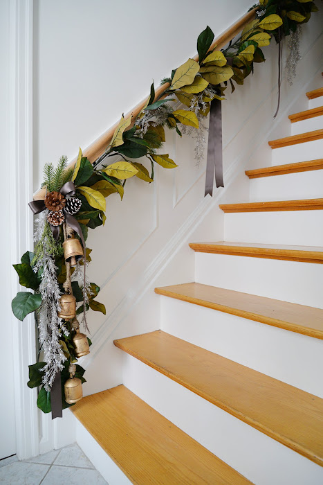 magnolia garland on stair handrail, brass bells, brown satin ribbon