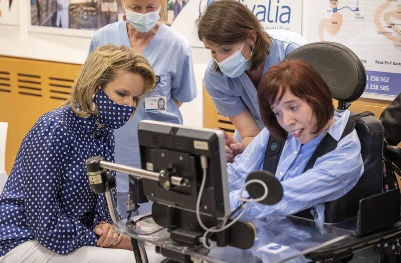 Queen Mathilde wore a navy polka-dot print tie neck blouse from Natan, and polka dot mask, white trousers