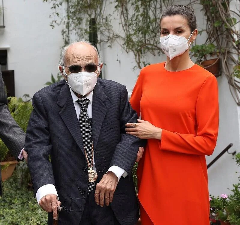 Queen Letizia wore an orange asymmetric outfit from Zara, and she carried red clutch by Angel Schlesser