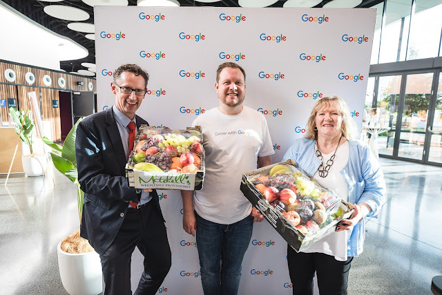Google Australia’s Richard Flanagan with Stephen Jones MP and Mayor Marianne Saliba in front of a Google sign, holding baskets of fruit