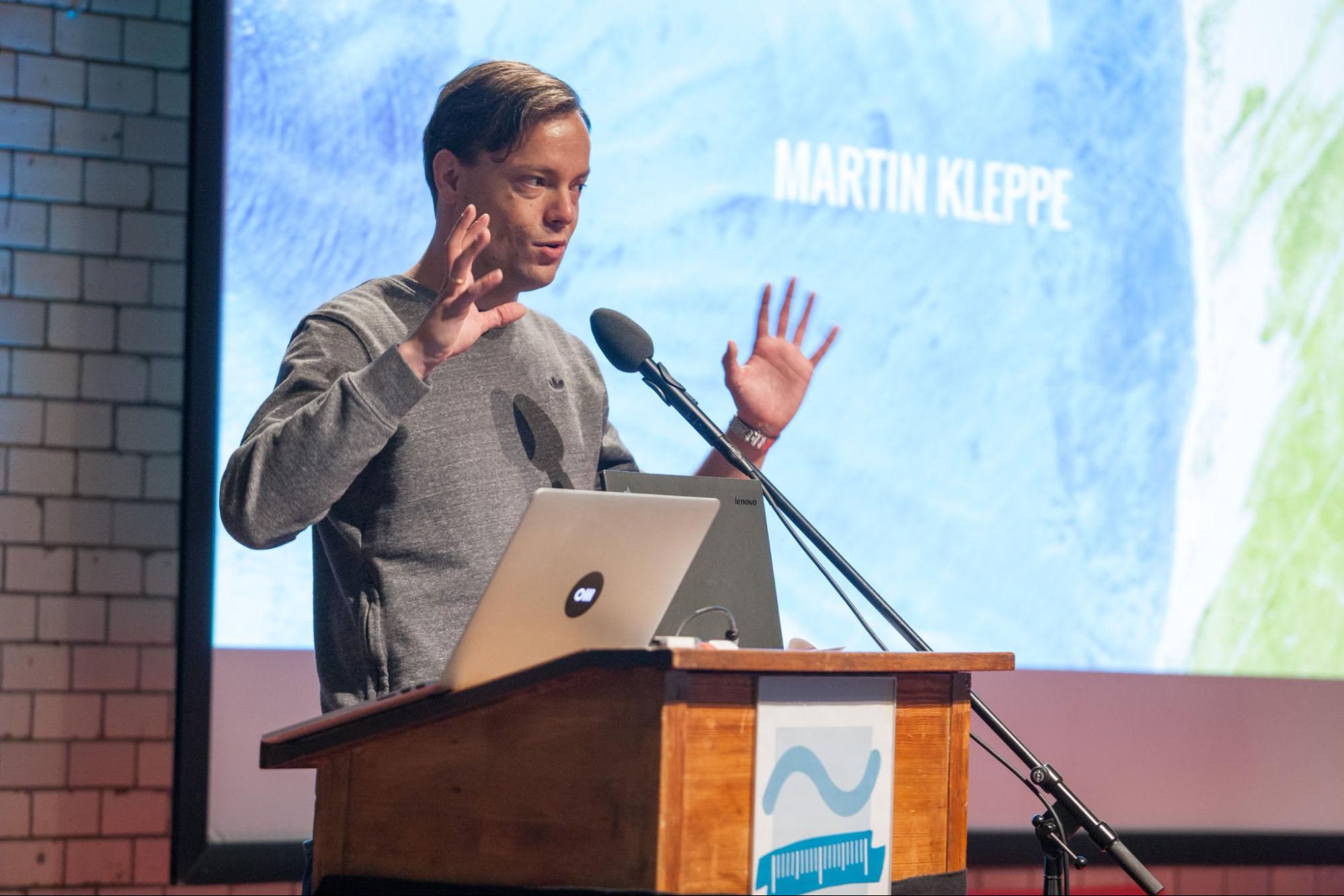 Image shows Martin Kleppe onstage behind his podium and laptop. His name is projected onto the screen behind him