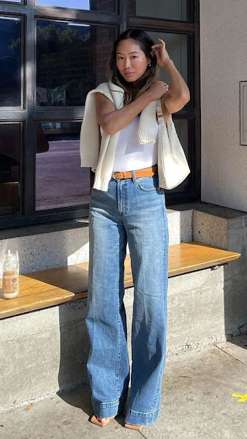 A woman weara jeans and plus a brown belt.