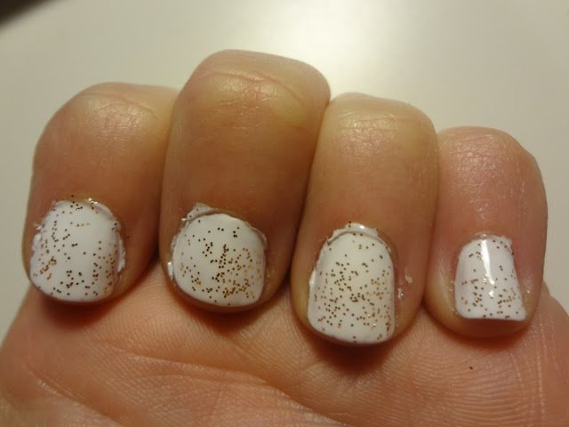 white nail polish with gold glitter over it