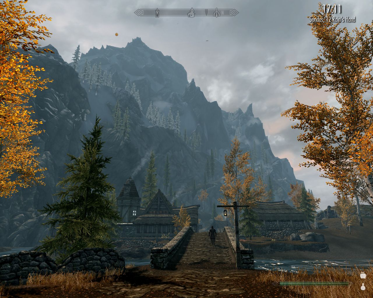 bridge leads across a river, houses of Ivarsted on the other side, high mountains in the distance