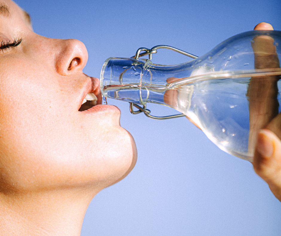 girl drinking water from glass bottle in sun