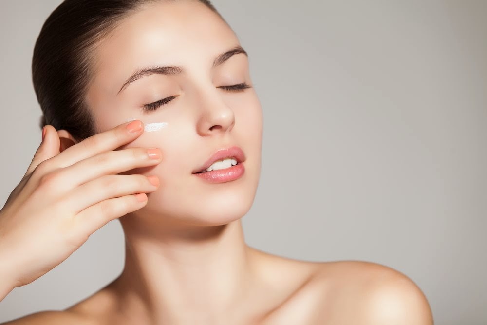 увлажнение кожи. девушка наносит крем на лицо. сохранить кожу увлажненной коже. сохранить кожу увлажненной коже. красивое лицо косметология.