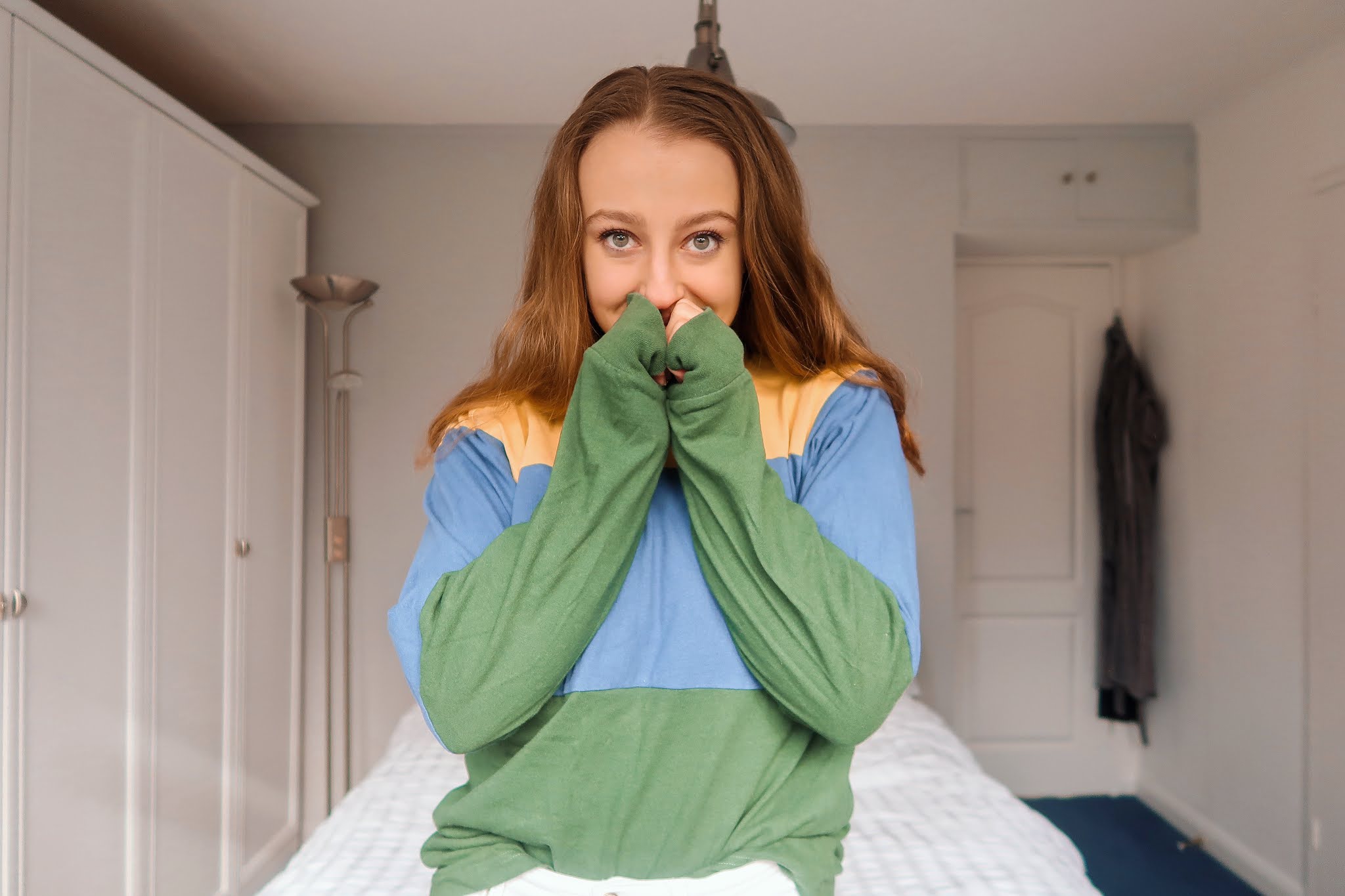 Georgie in her bedroom wearing a colourful second-hand striped top