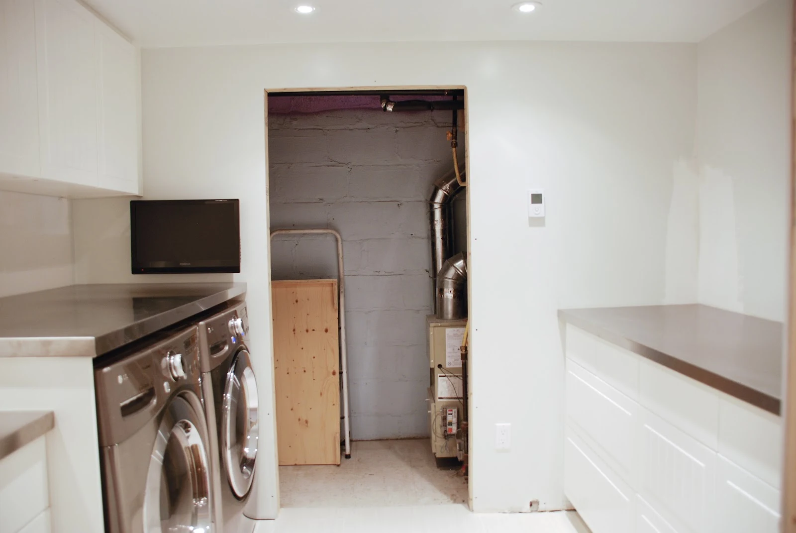 counter over front load washer and dryer, galley laundry room, stainless steel countertop in laundry room, floating countertop in laundry room