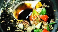 Pouring soya sauce in stir fried vegetables and herbs for chilli chicken gravy