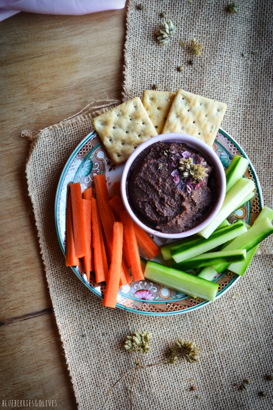 vegetable spread in pink bowl with crudités and a wood table with old tablecloth