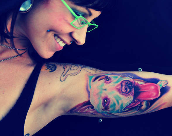 Simpática imagen de una joven enseñando su tatuaje. Un tatuaje de perro en su brazo