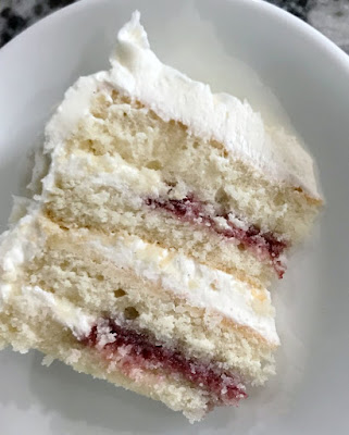 slice of cake with 4 layers of white cake, white frosting and raspberry filling