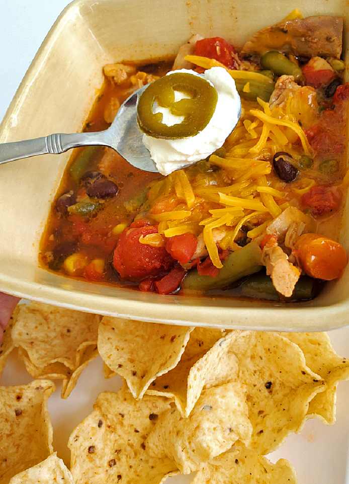 Southwestern Chicken Chili this is a bowl of southwest soup with chips, sour cream and jalapenos