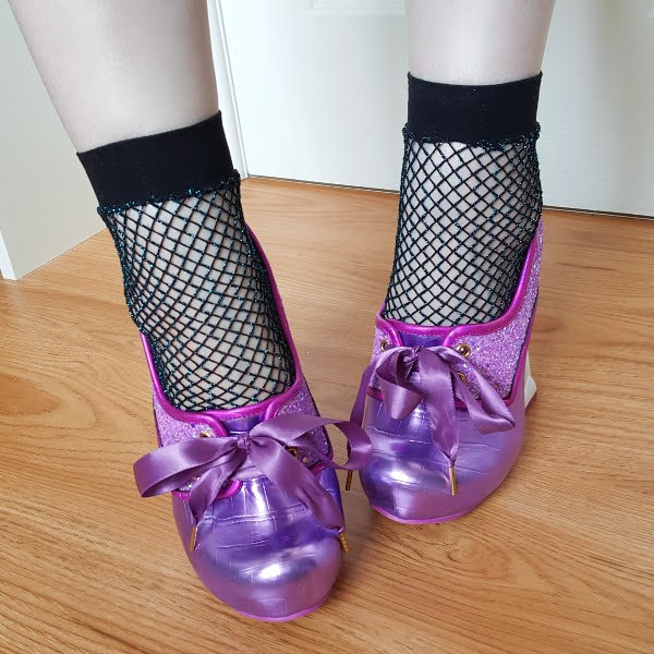 feet wearing purple metallic shoes with fishnet socks and ribbon ties