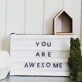 Modern dolls' house miniature scene with a light box (with the words 'You are awesome' on it), grass bunny, house-shaped wall box and a geometric marble vase.