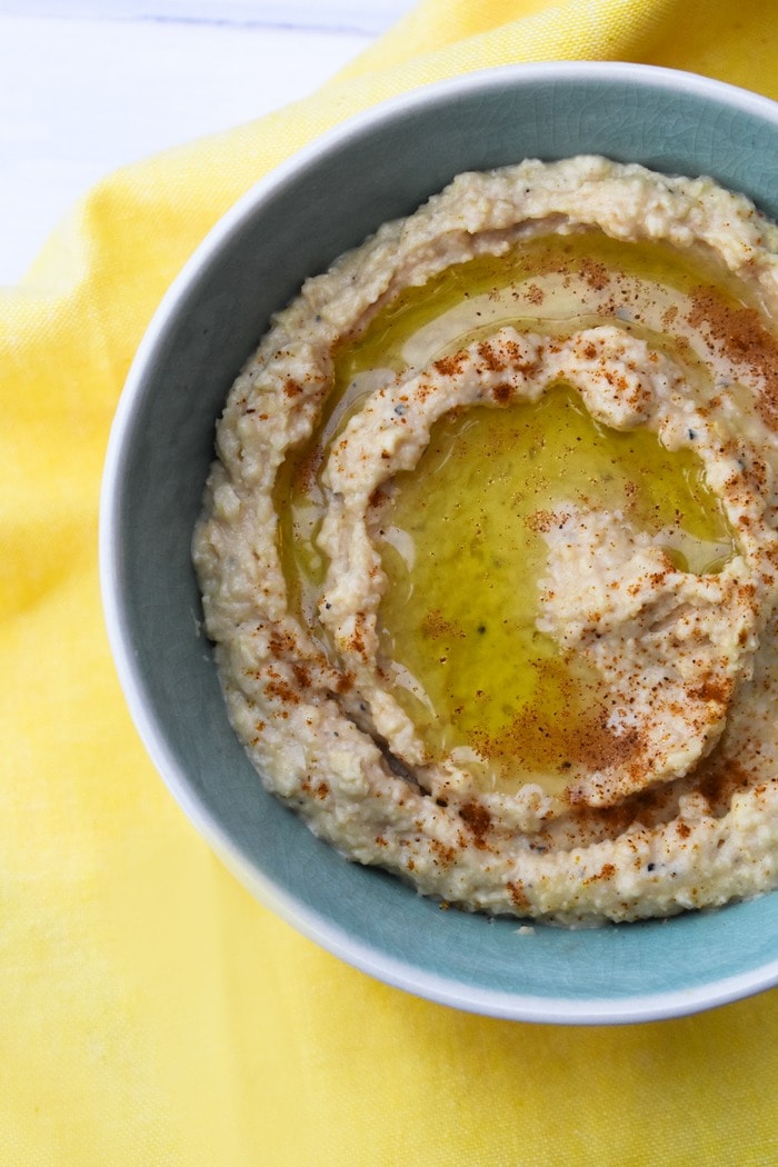 close-up of homemade hummus, topped with a swirl of olive oil and a sprinkle of cayenne pepper