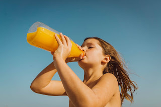 Image of a young girl trying to get her vitamin c by drinking orange juice out of a 2lt bottle