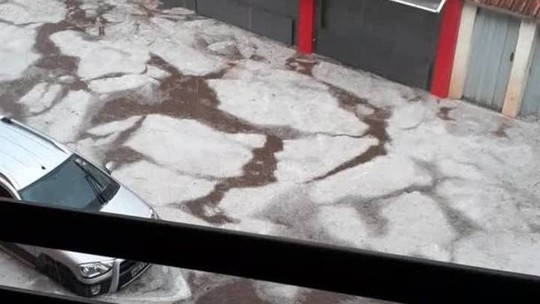 Rua é tomada por placas de granizo após rio alagar em MG