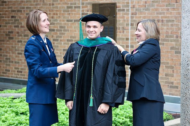 Air Force Col. (Dr.) Pamela Williams (left) and Army Lt. Col. (Dr.) Ashley Maranich (right) adorn Dmitriy Treyster, a 2021 graduate of USU's F. Edward Hébert School of Medicine, with his Doctor of Medicine academic hood. (Image credit: Courtesy of Army Sgt. Cory Long, USU)