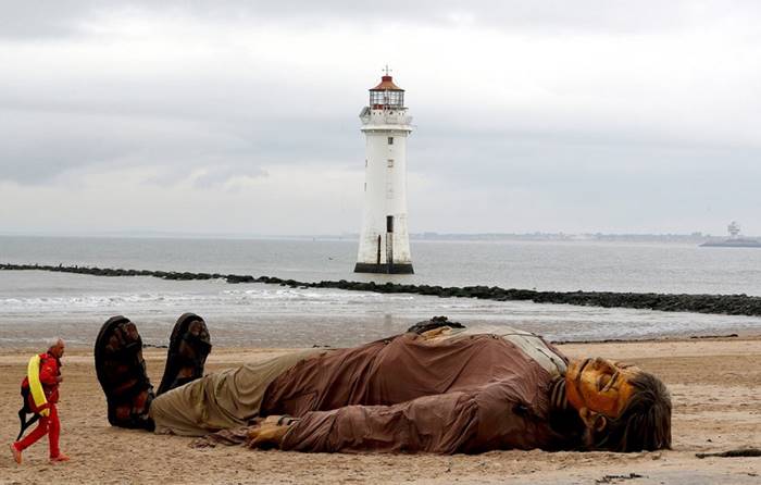 The rescuer passes by a huge puppet of the French street theater Royal de Luxe. New Brighton, UK, October 5th. By: Darren Staples