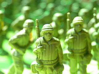 Stock photo of green plastic army men. One is in sharp focus and facing the camera, while a great many others seem to be grouped facing in various directions.