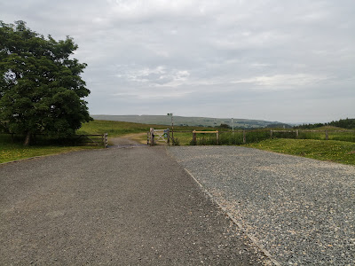View from our motorhome into rolling countryside. A wide footpath stretches ahead over a cattle grid.