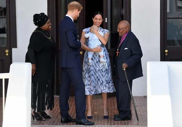 Meghan Markle wore Clup Monaco dremah silk midi dress and Everlane essential goweave jumpsuit. Gas earrings