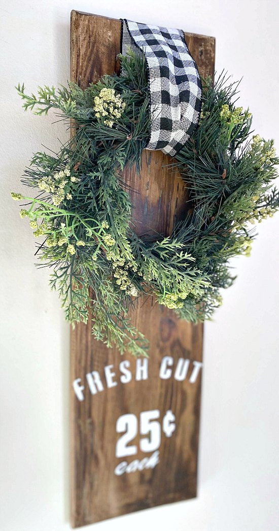 Wreath hanging on reclaimed wood with buffalo checked ribbon