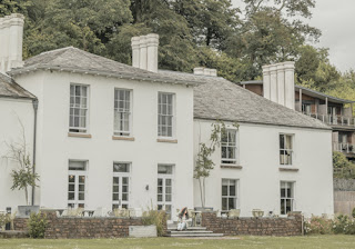 a girl sits on the steps on the terrace, behind her is the white Cornwall Hotel