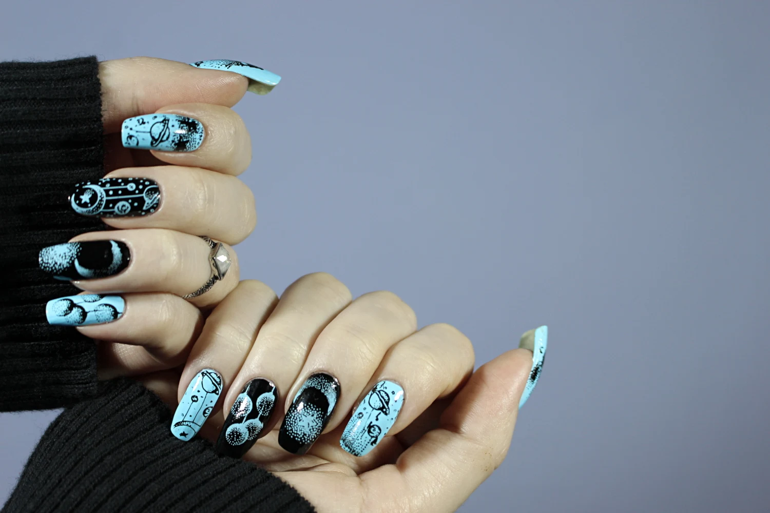 a close-up of long, natural nails with celestial blue and black design inspired by cosmic witch