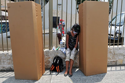 mujer lloraba sentada junto a cajas de carton usadas como ataúdes.