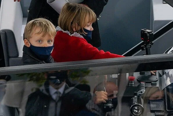 Princess Gabriella wore a red sweater. Princess Charlene wore a tropicalia toile de jouy opera coat from Christian Dior. Louis Vuitton boots