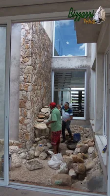 Bizzarri, da Bizzarri Pedras, fazendo a execução de uma cascata de pedra com pedra do rio no lago ornamental para carpas em jardim de inverno em sala de estar de residência em condomínio em Atibaia-SP com a parede de pedra moledo. 08 de novembro de 2016.