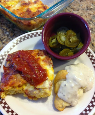 tater tot breakfast casserole topped with salsa, small bowl of jalapenos and a gravy covered crescent roll on plate