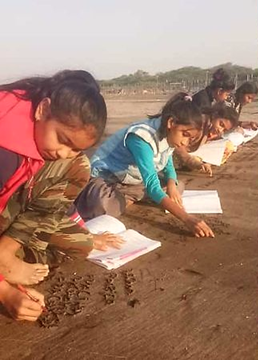 Girls of onjal village use sand surface as a notebook to write the lessons
