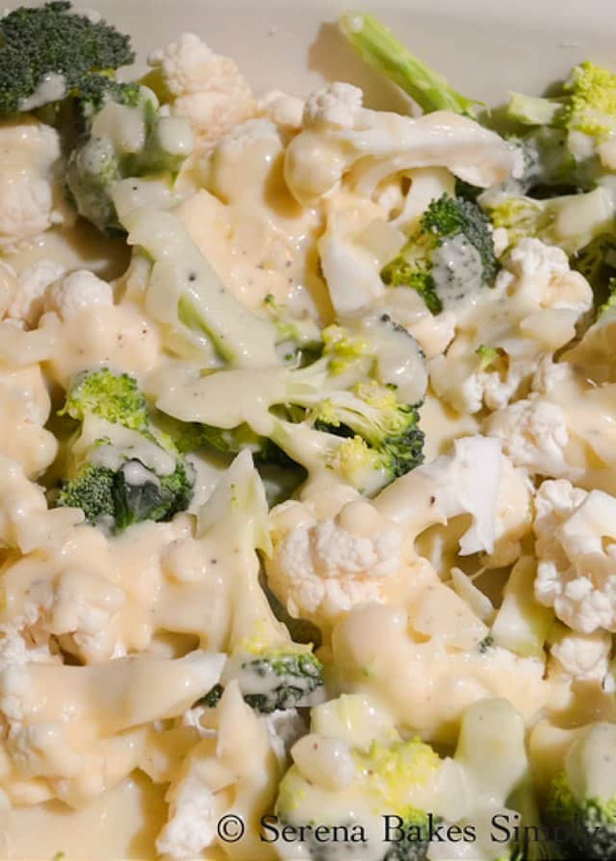 Broccoli Cauliflower in a large pan topped with cheese sauce.