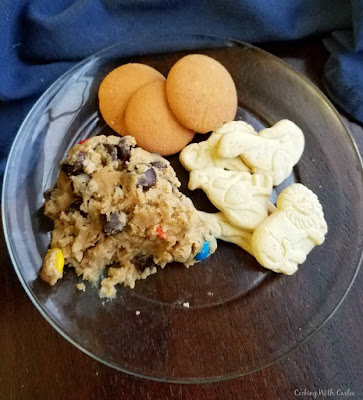 glass plate with scoop of monster cookie dip, animal crackers and vanilla wafers