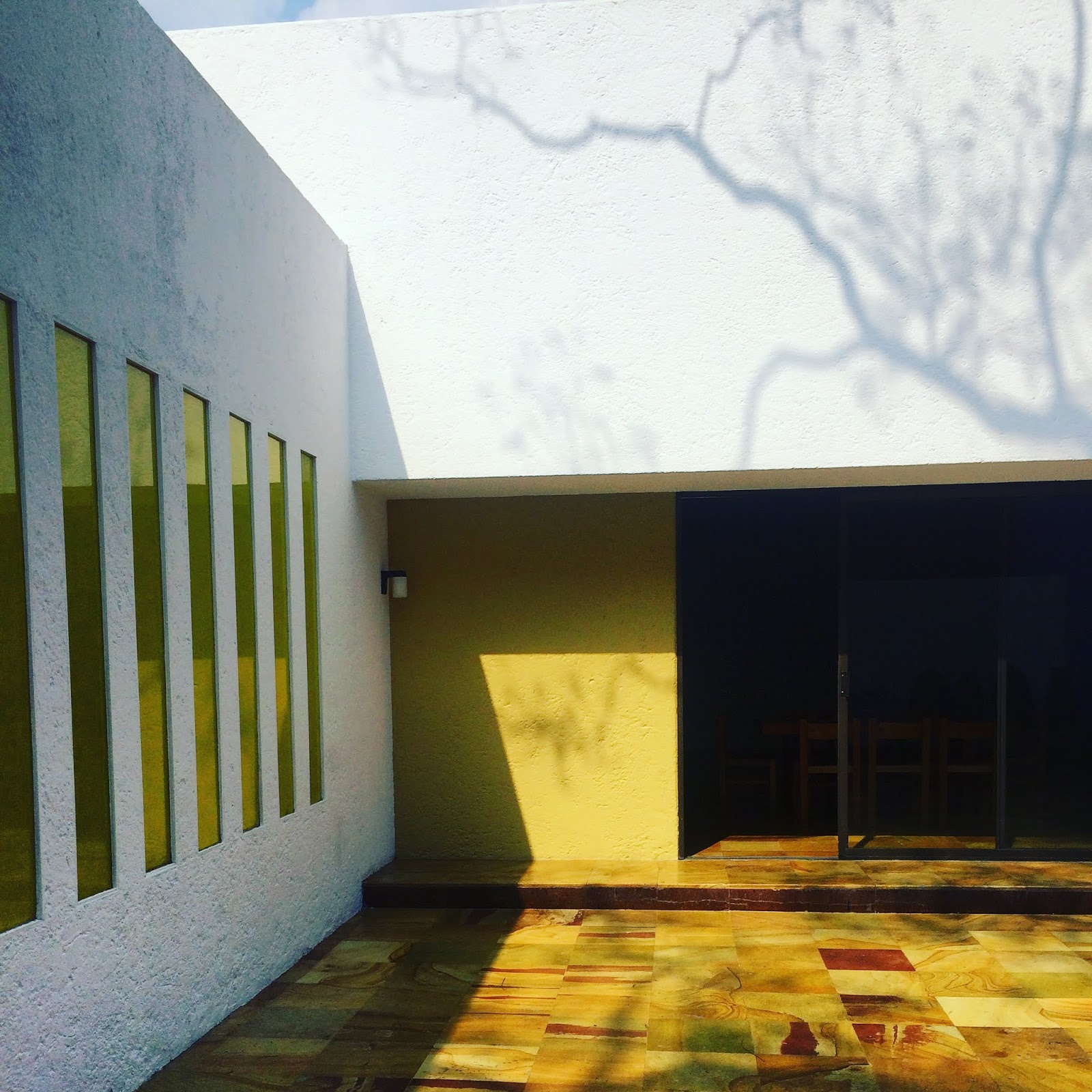 tree shadow on white walls with yellow windows and patio