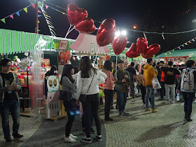 people selling red heart-shaped balloons