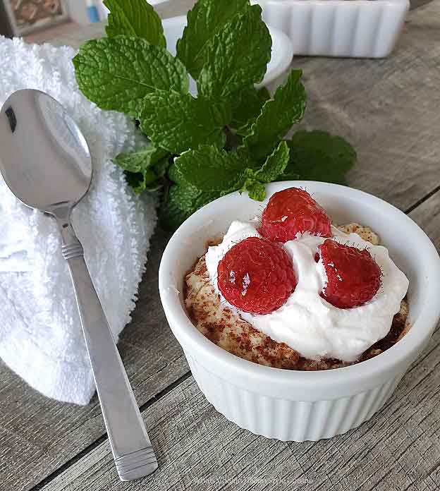 baked custard in a ramekin with raspberries and cream on top