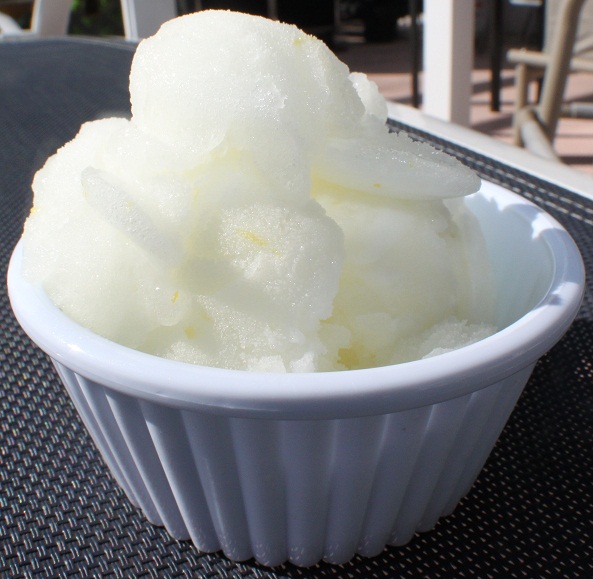Italian lemon ice is a frozen Italian lemon confection that freezes into a creamy lemon almost sherbet style ice cream. The ice is very popular in Italian. this lemon ice is in a white ice cream dish 