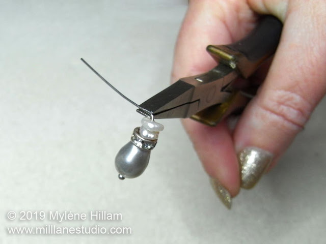 Bending the head pin at a 90° angle above the pearls.