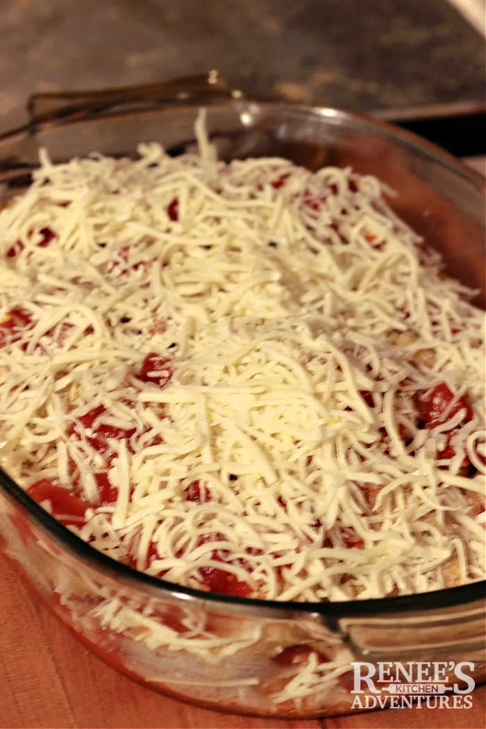 Unbaked Eggplant Parmesan ready for the oven in a casserole dish with cheese on top