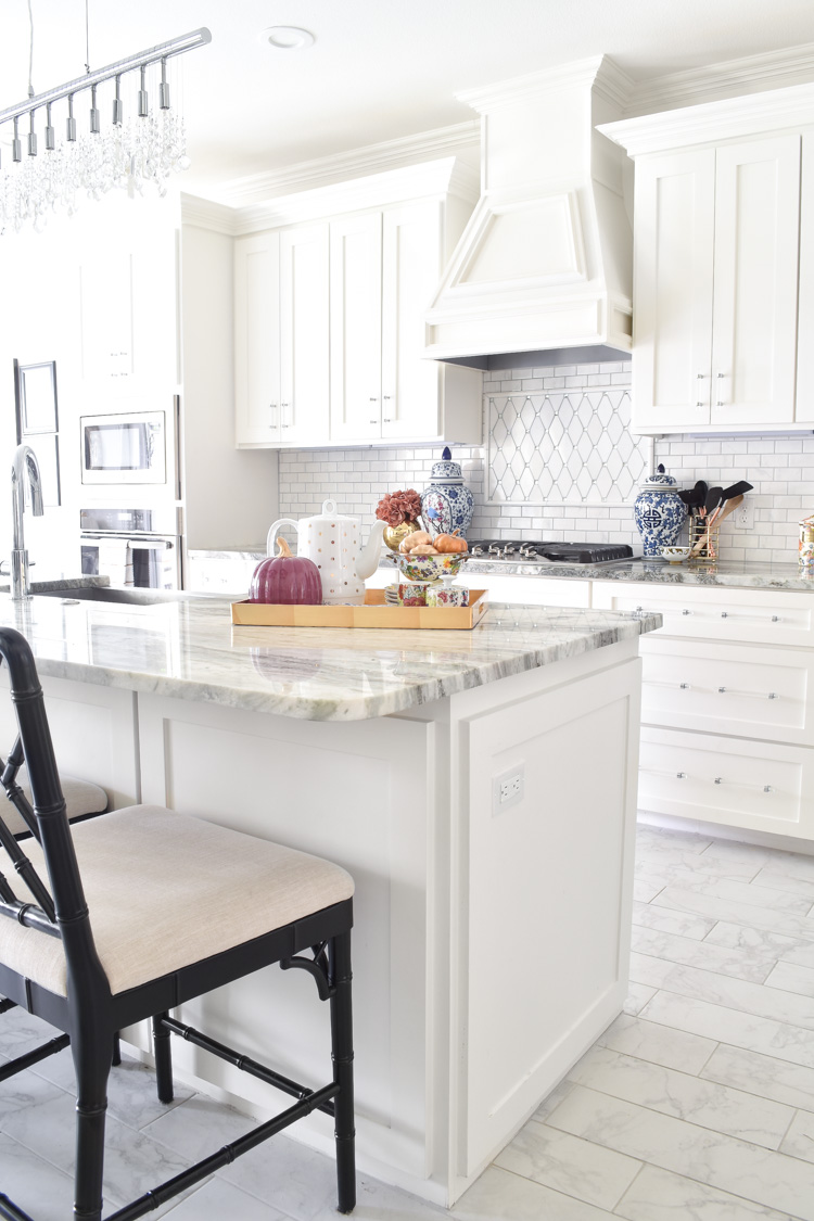 White shaker cabinet kitchen with marble countertops, blue and white ginger jars, and lucite cabinet hardware and pulls. #whitekitchen #brightkitchen #shakercabinets