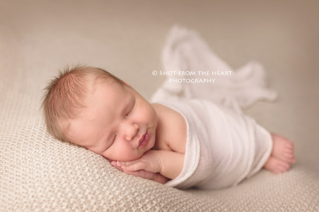 newborn baby making faces on cream blanket photography