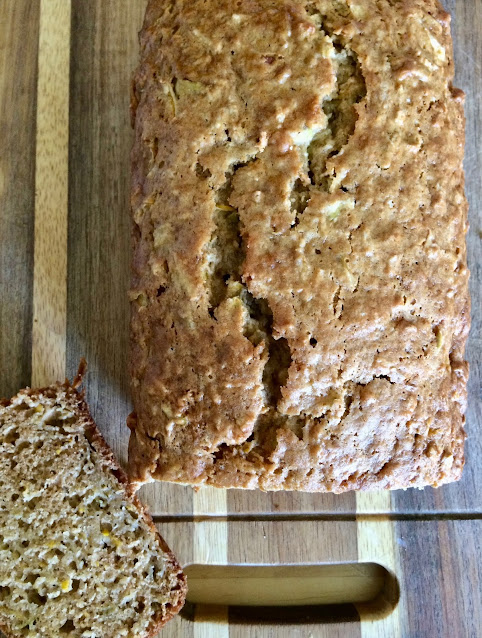 Finished loaf of yellow squash and apple bread on a cutting board.